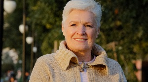 Closeup head shot portrait middle aged senior retired woman standing posing outdoors, enjoying weekend lazy time in park. Pleasant beautiful happy healthy older mature grandmother looking at camera